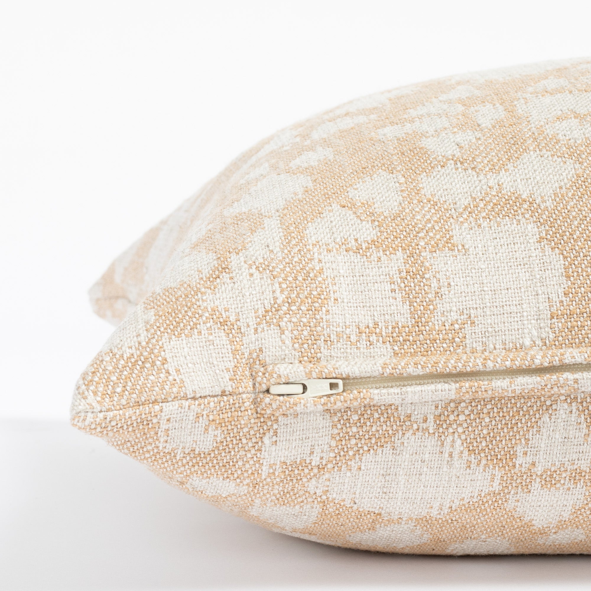 a soft gold and cream abstract floral patterned throw pillow: close up zipper detail