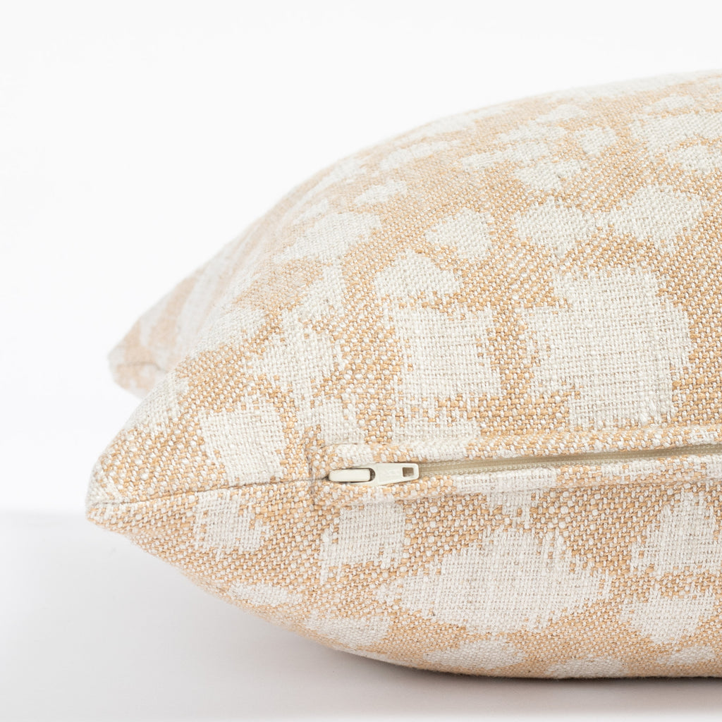 a soft gold and cream abstract floral patterned throw pillow: close up zipper detail