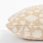a soft gold and cream abstract floral patterned throw pillow: close up side view