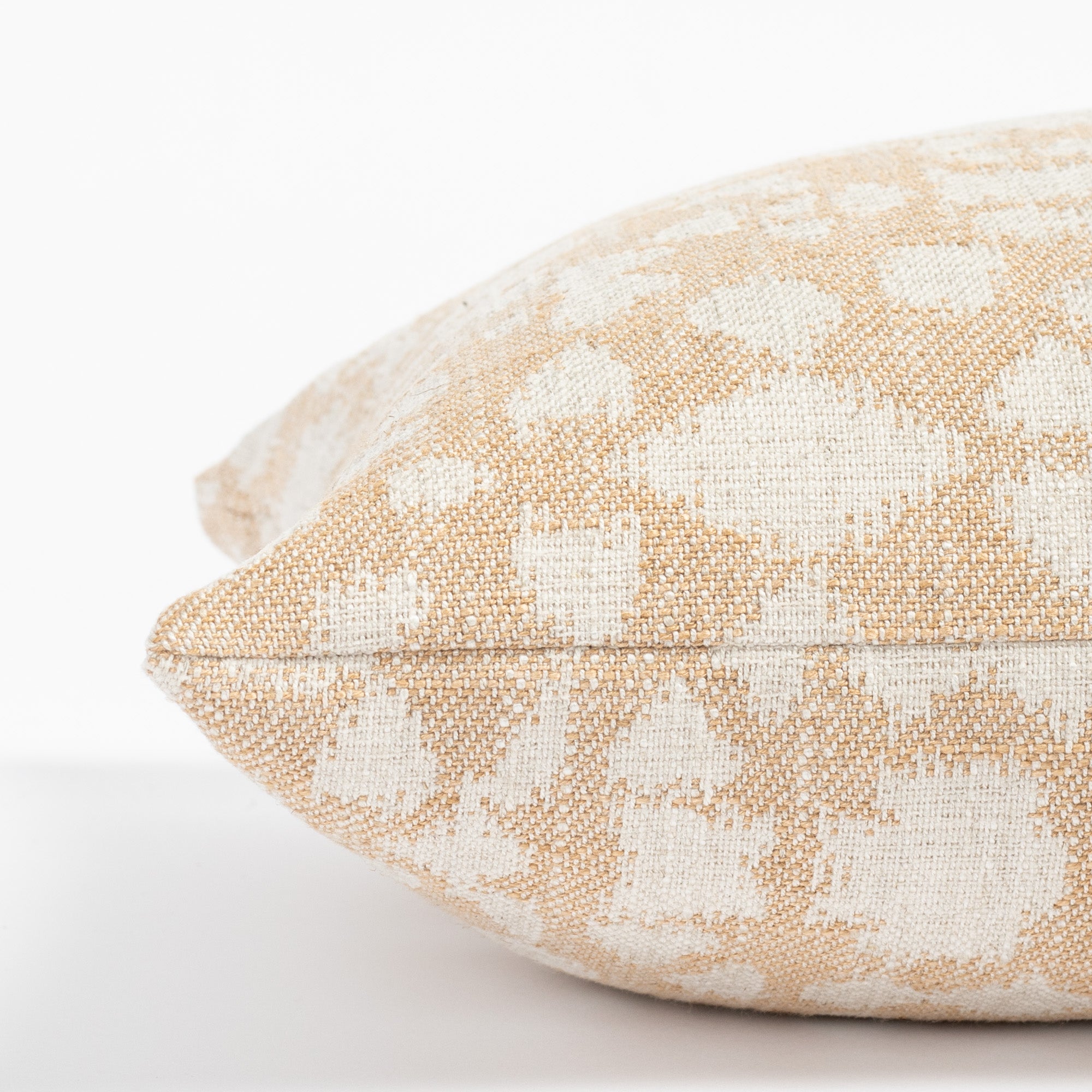 a soft gold and cream abstract floral patterned throw pillow: close up side view