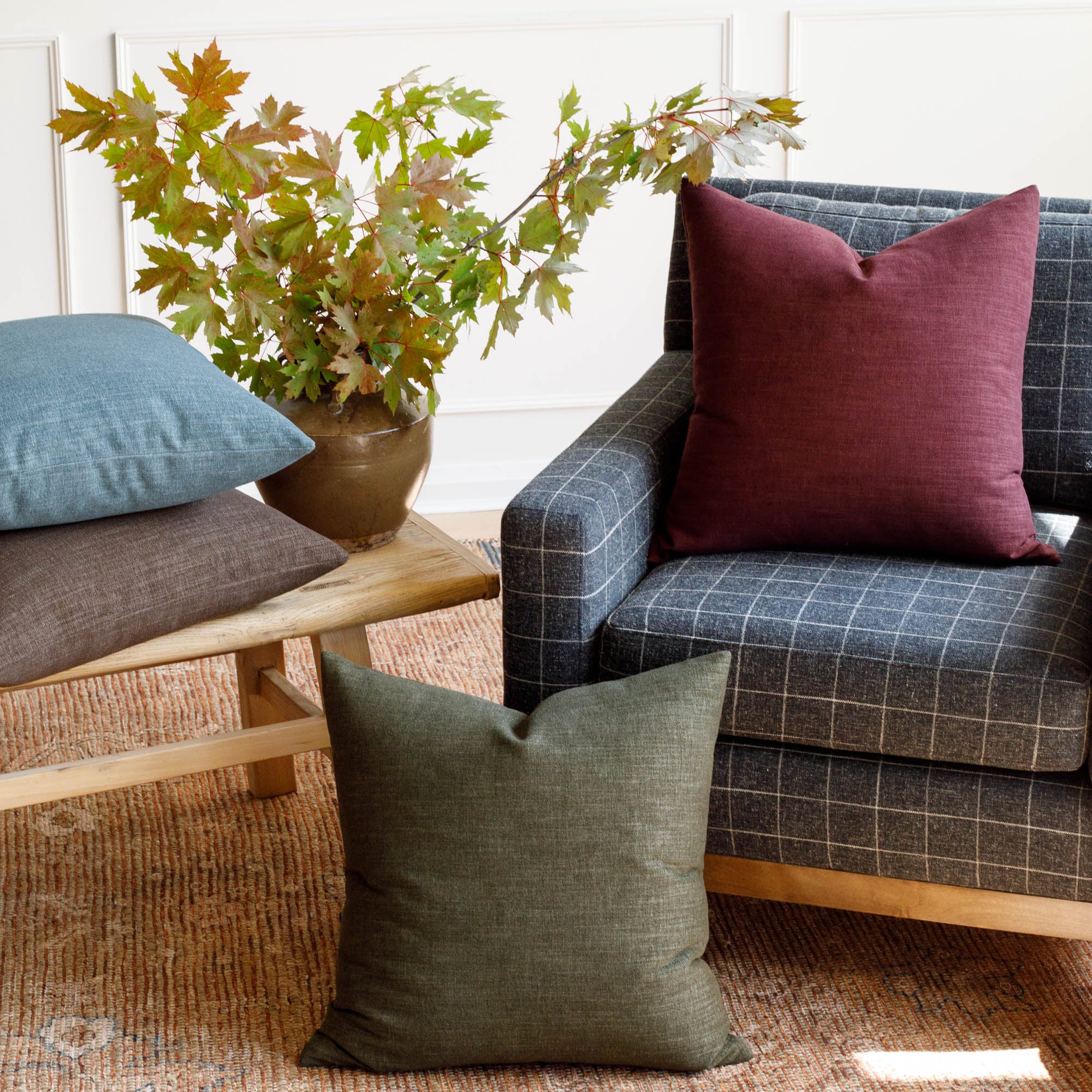 Tonic Living Bedford 22x22 pillows in Merlot, Moss, Coffee, and Denim styled together in a living room scene.