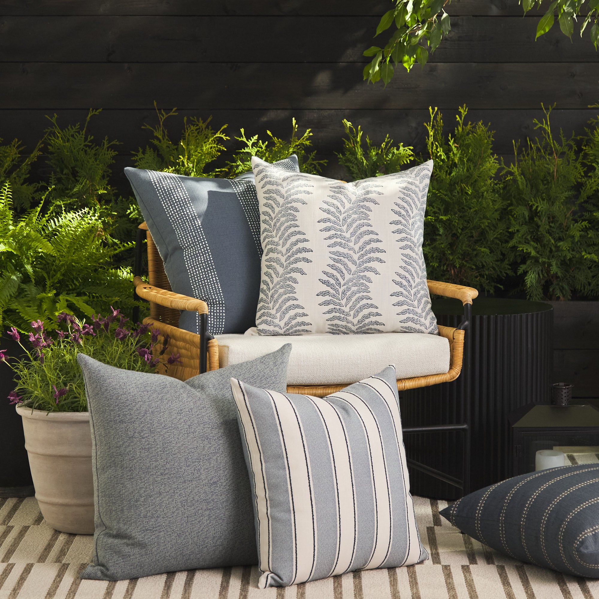 Tonic Living outdoor pillow collection styled on a patio in blue, white, and coastal-inspired tones.