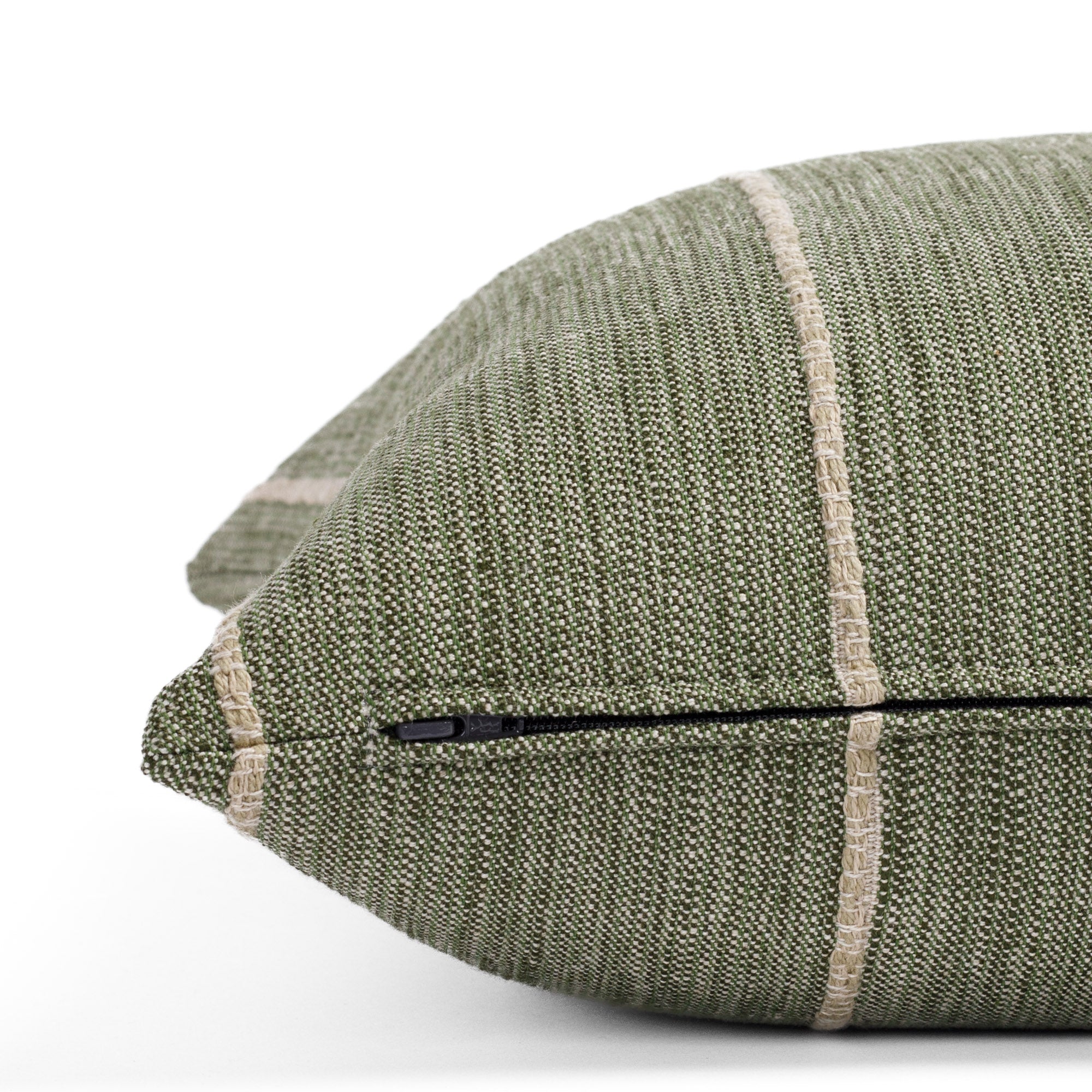 a leafy green throw pillow with a chunky natural stripe: close up zipper view