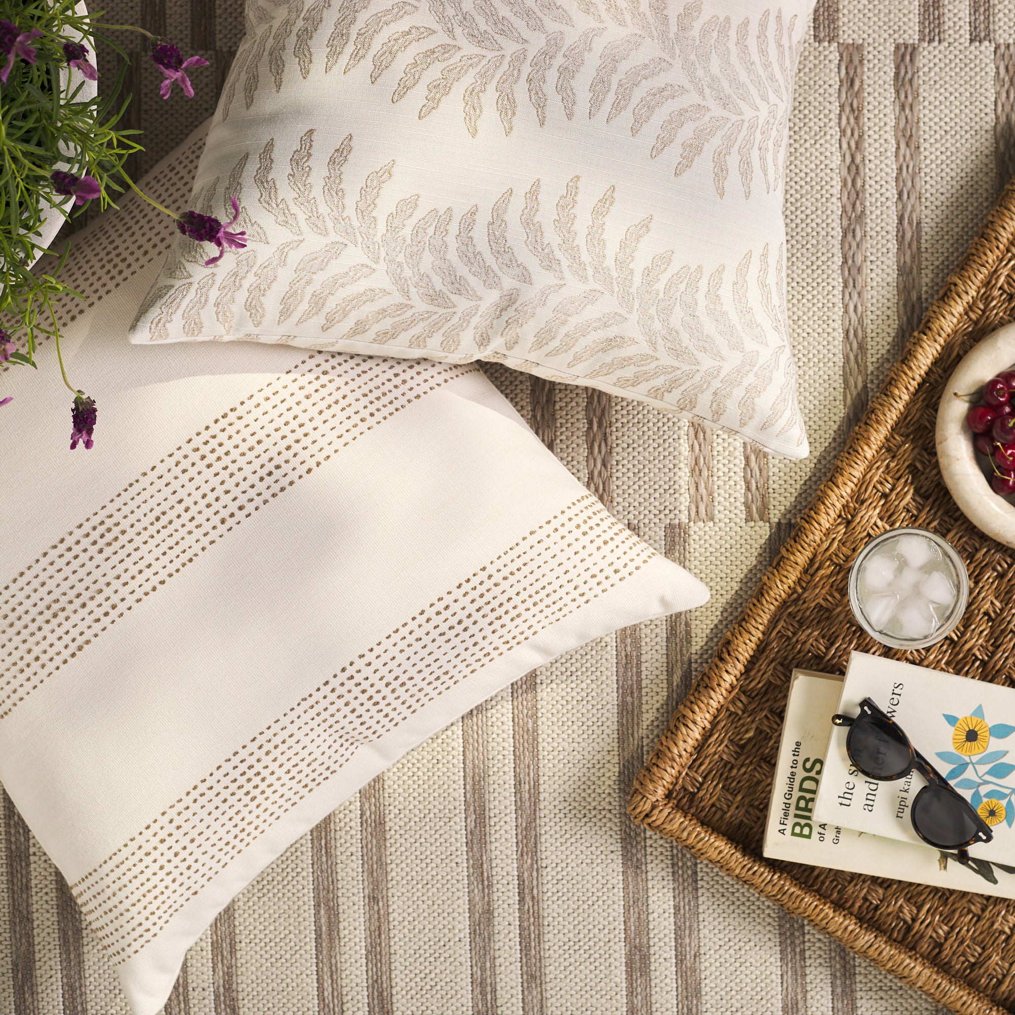 Overhead view of Tonic Living Swoon Sand decorative cushion with Caper Linen pillow on an outdoor rug.