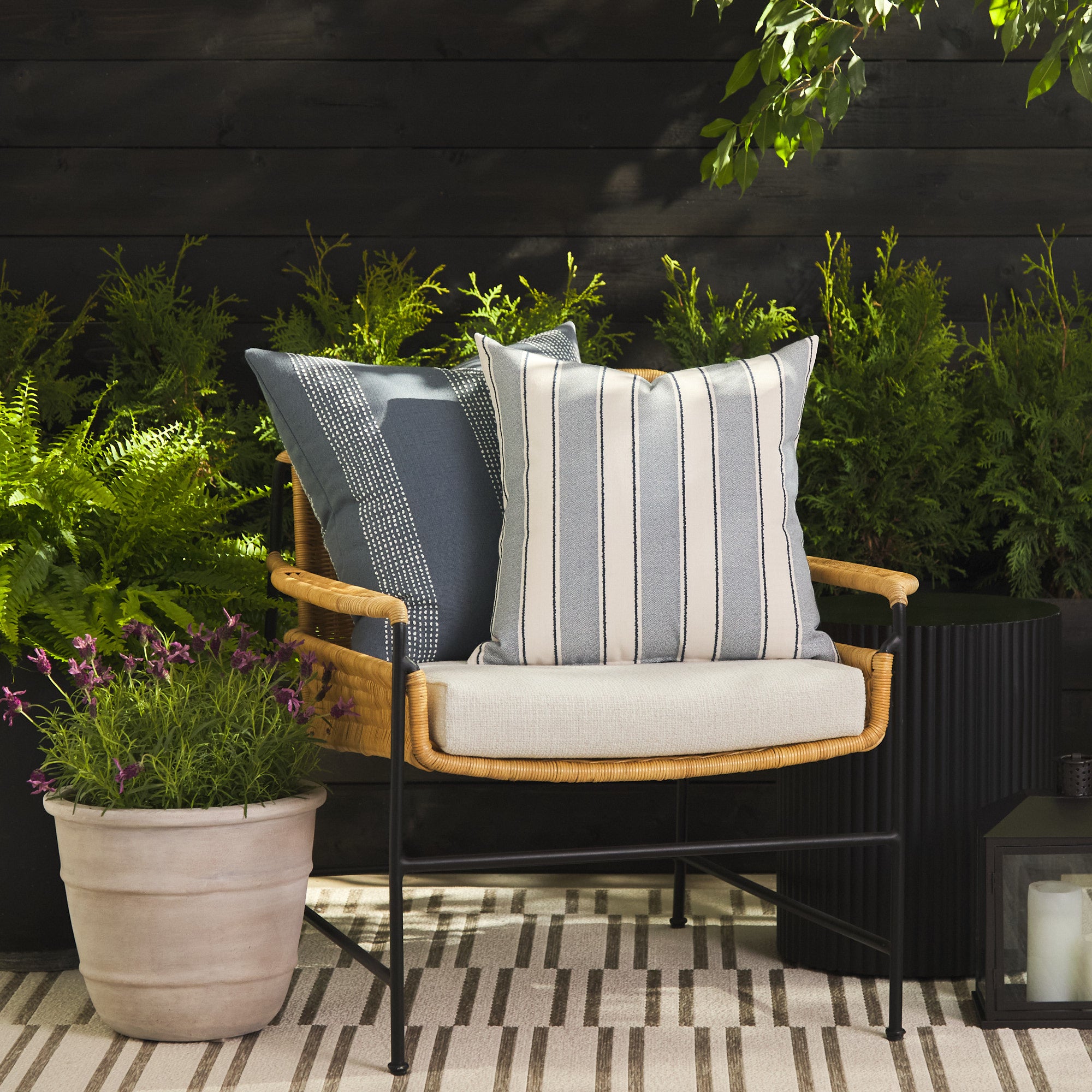 Tonic Living Sentiment Denim outdoor cushion styled on a chair with Caper Slate 22x22 pillow in a blue outdoor setting.