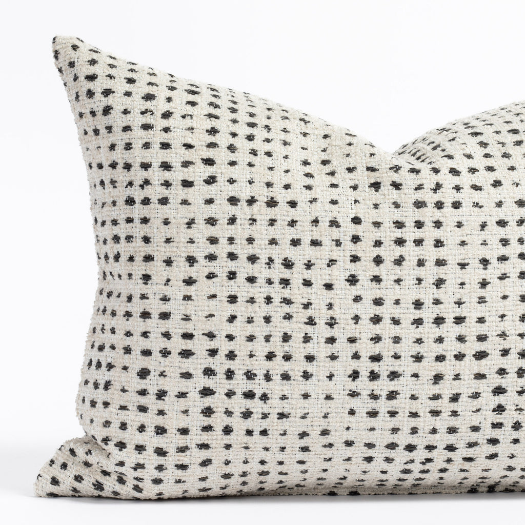 a cream and black polka dot patterned throw pillow : close up view