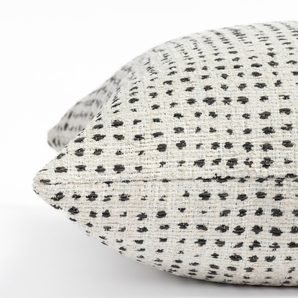 a cream and black polka dot throw pillow : close up side view