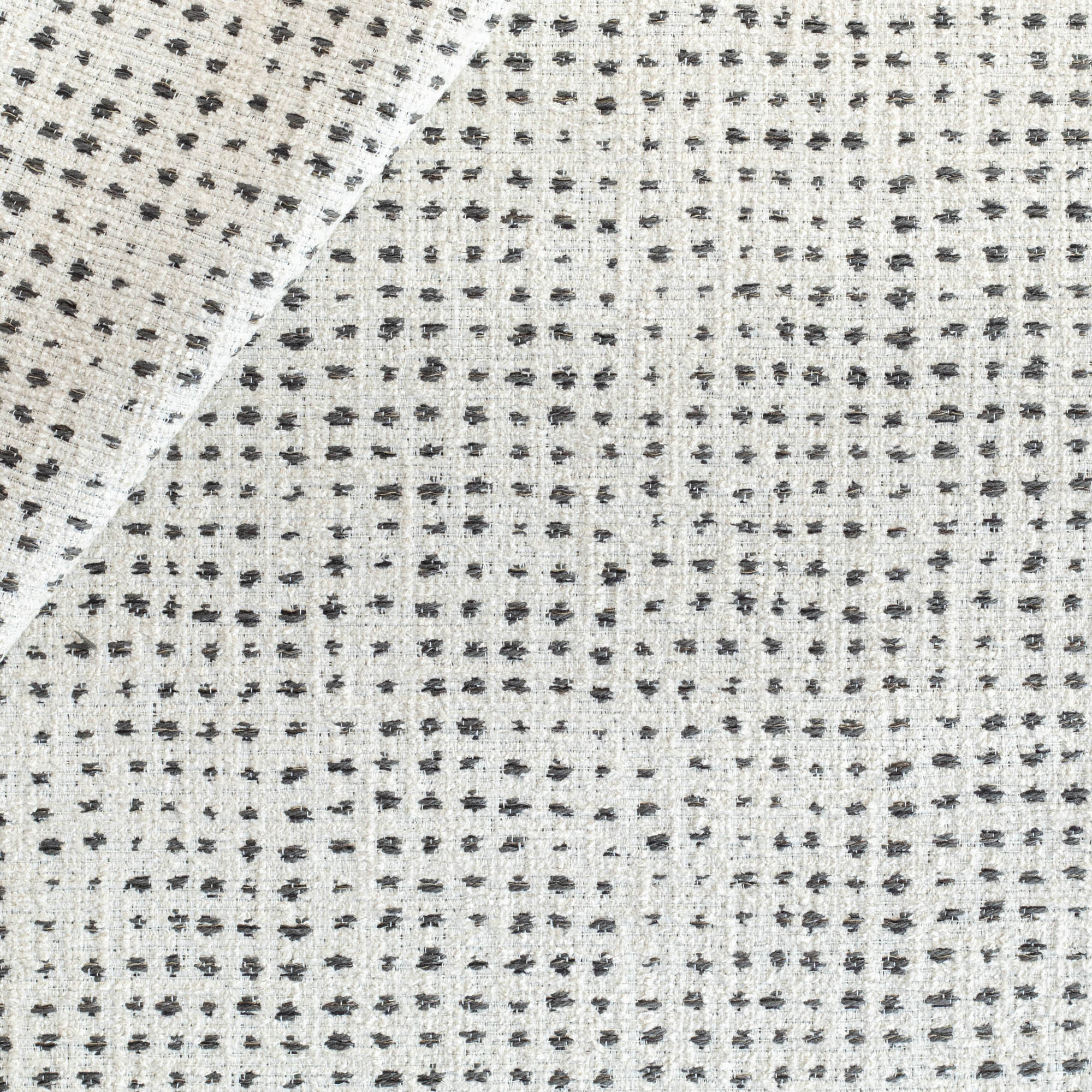 an off-whitee and black variegated polka-dot patterned textured upholstery fabric