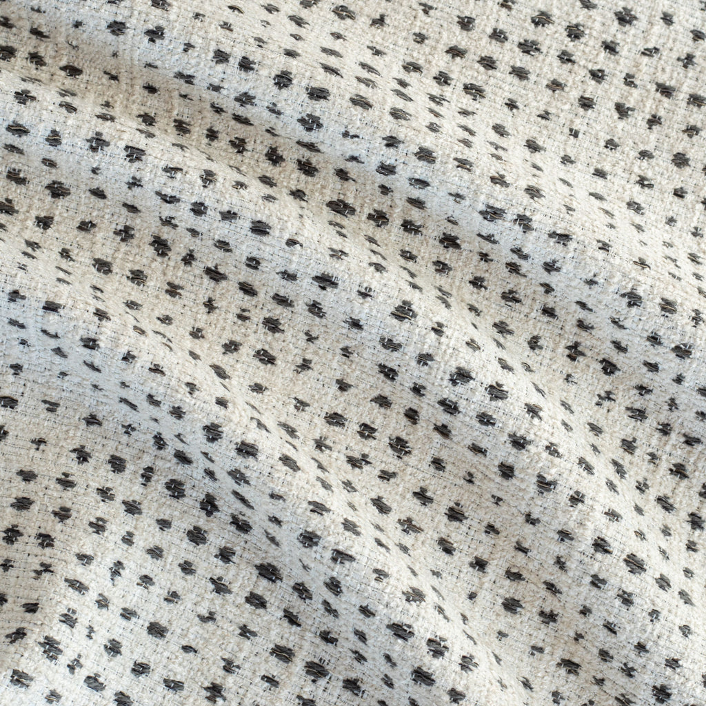 an off-whitee and black variegated polka-dot patterned textured home decor fabric