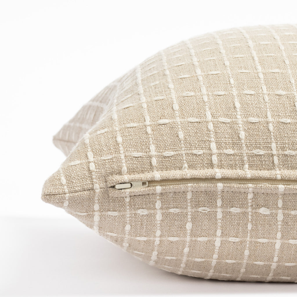 a beige flax with cream stitched windowpane patterned throw pillow: close up zipper view