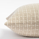 a beige flax with cream stitched windowpane patterned throw pillow: close up side view