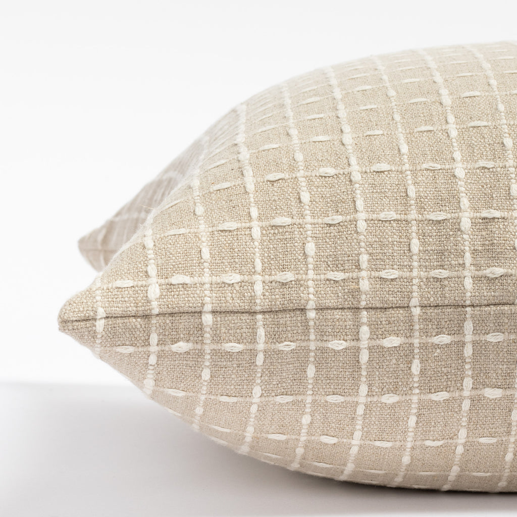 a beige flax with cream stitched windowpane patterned throw pillow: close up side view