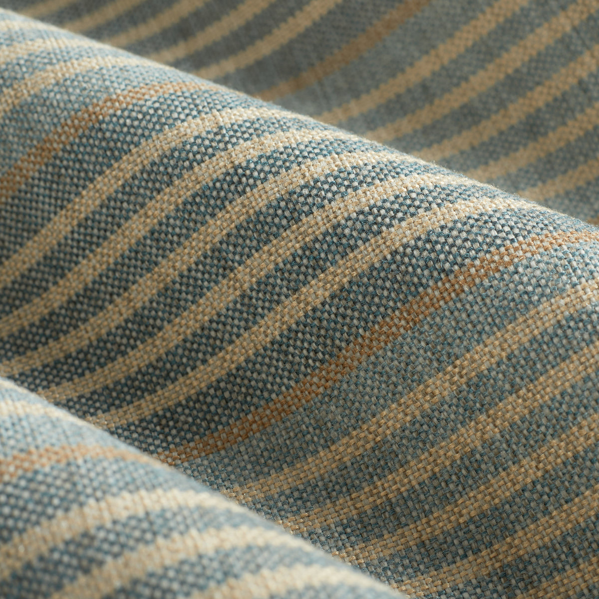 Close up of Tonic Living Clark Stripe Pool fabric showing faded blue, oatmeal, and camel stripes with woven texture.