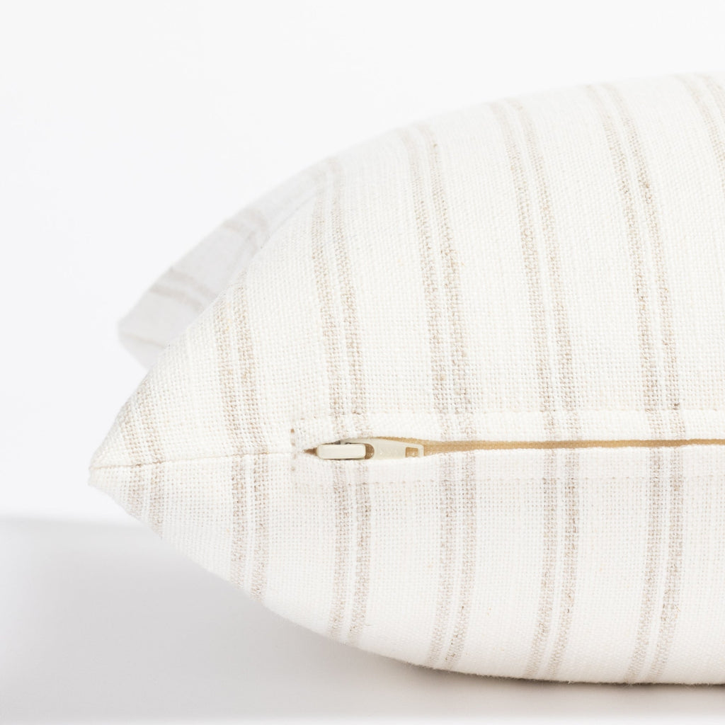 a soft white and beige stripe lumbar pillow : close up zipper view
