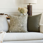 Moss green floral pillow on a cream sofa