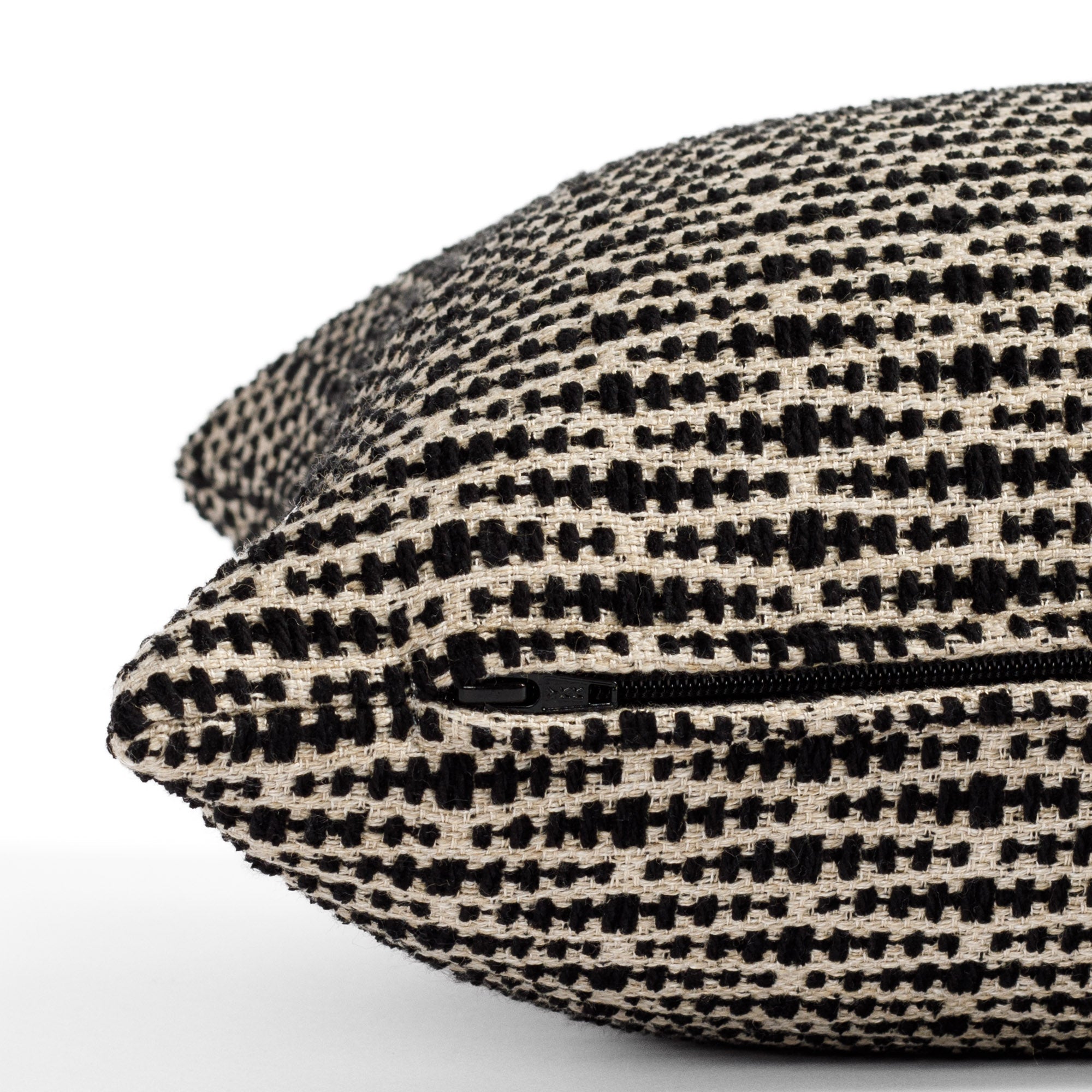 a black and tan geometric patterned lumbar pillow : close up zipper view