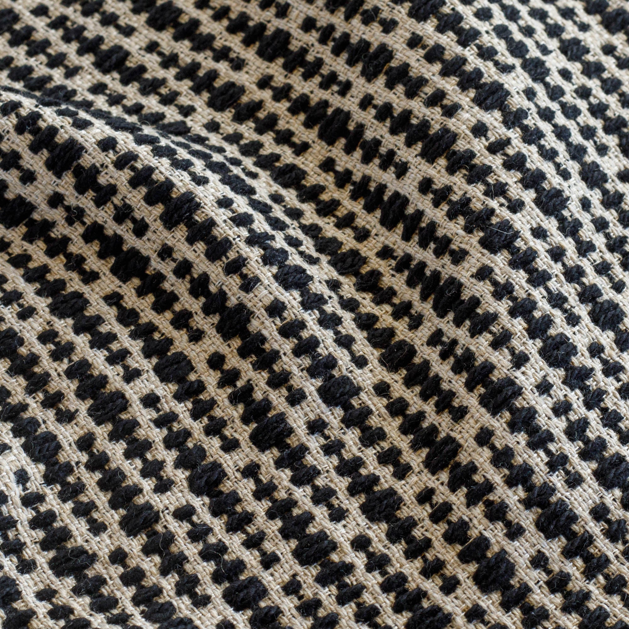 a black and tan textured geometric patterned home decor fabric : close up view