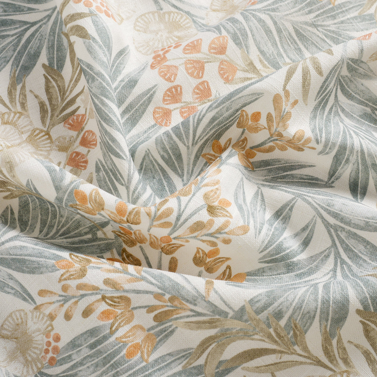 Close up of Tonic Living Fable Meadow drapery fabric showing its leafy botanical design in blue, terracotta, light brown, and soft white.