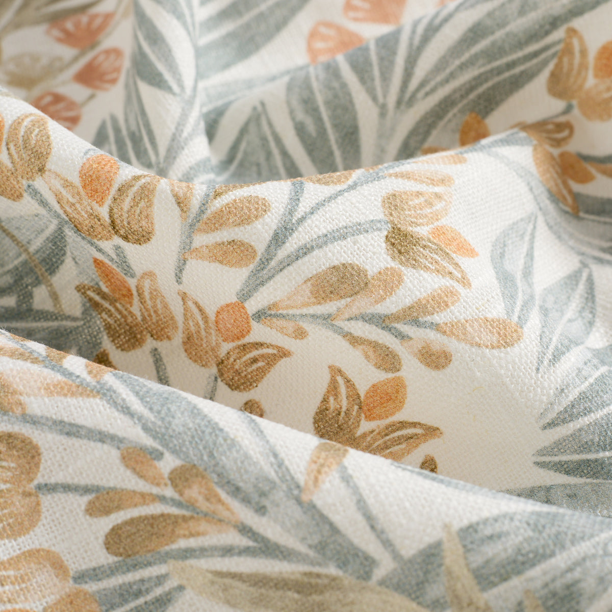 Close up of Tonic Living Fable Meadow curtain fabric showing its floral botanical design in blue, terracotta, light brown, and soft white.