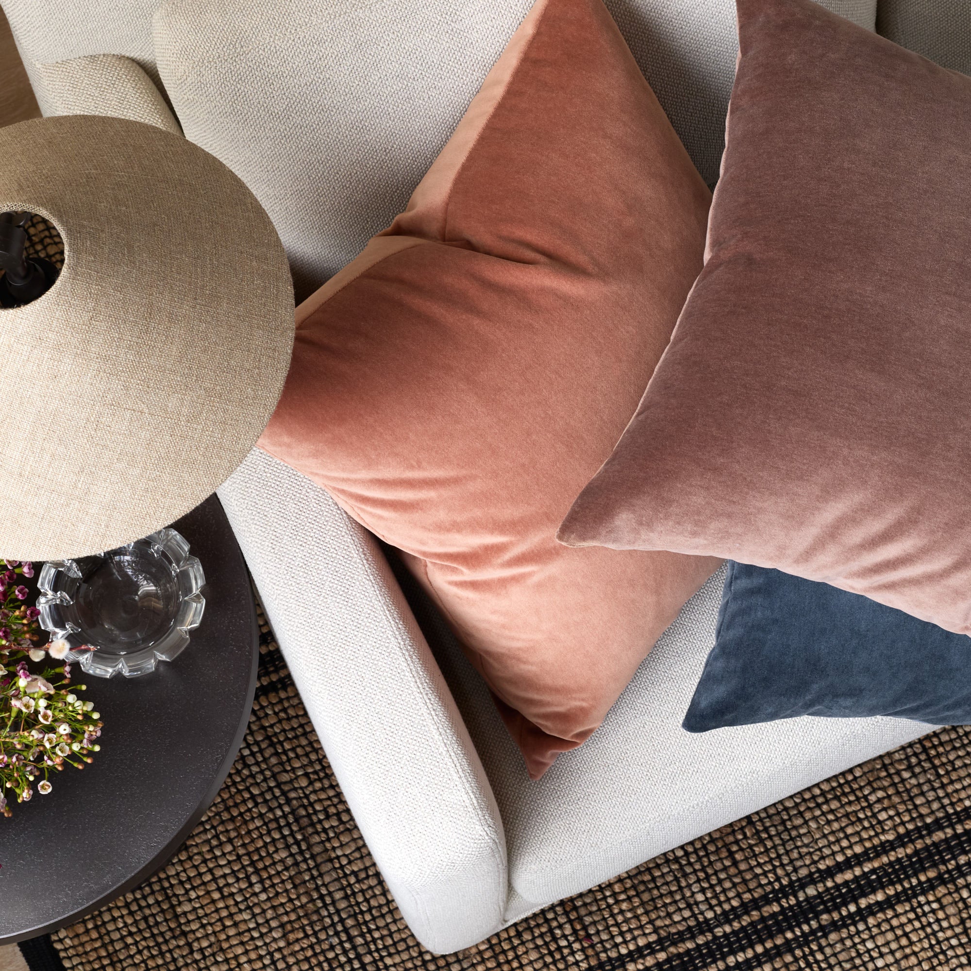 Overhead view of Tonic Living Florence Velvet pillows in pink, purple, and blue stacked on a sofa.