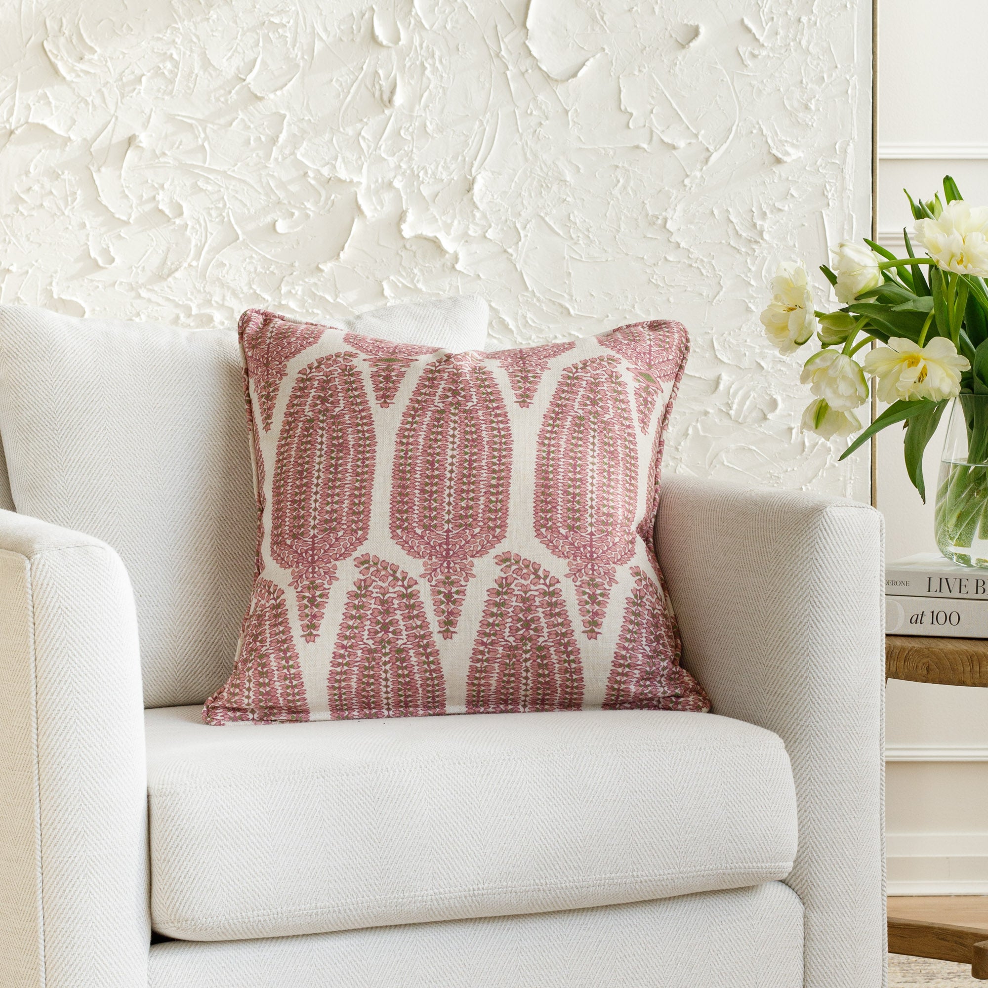 Pink and white lumbar pillow with a botanical pattern and piping detail, styled on a white chair (Georgia Orchid Pink by Tonic Living).