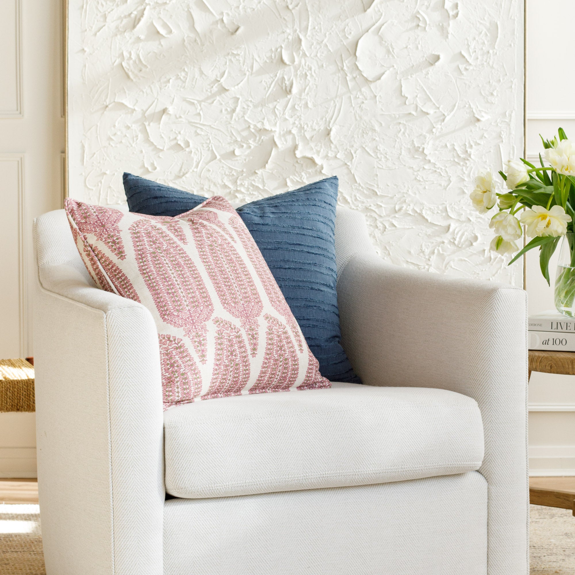 Two designer throw pillows styled on a white chair (Georgia Orchid Pink & Malibu Stripe Navy by Tonic Living).