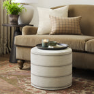 Tonic Living Gibson Stripe Birch round ottoman styled as an accent table in a warm neutral living room with coordinating throw pillows.