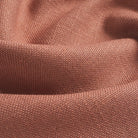 Close up of Tonic Living Hampton Rosewood upholstery fabric showing its earthy rose colour, terracotta tones, and linen-like woven texture.