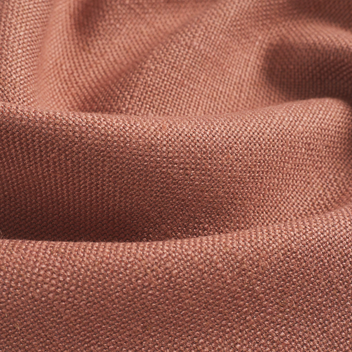 Close up of Tonic Living Hampton Rosewood upholstery fabric showing its earthy rose colour, terracotta tones, and linen-like woven texture.