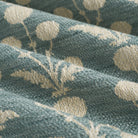 Close up of Tonic Living Hazel Pool upholstery fabric showing its muted blue-green and beige floral pattern with leafy stems and blooms.