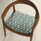 Tonic Living Hazel Pool botanical upholstery fabric shown on a dining chair seat in muted blue-green and beige.