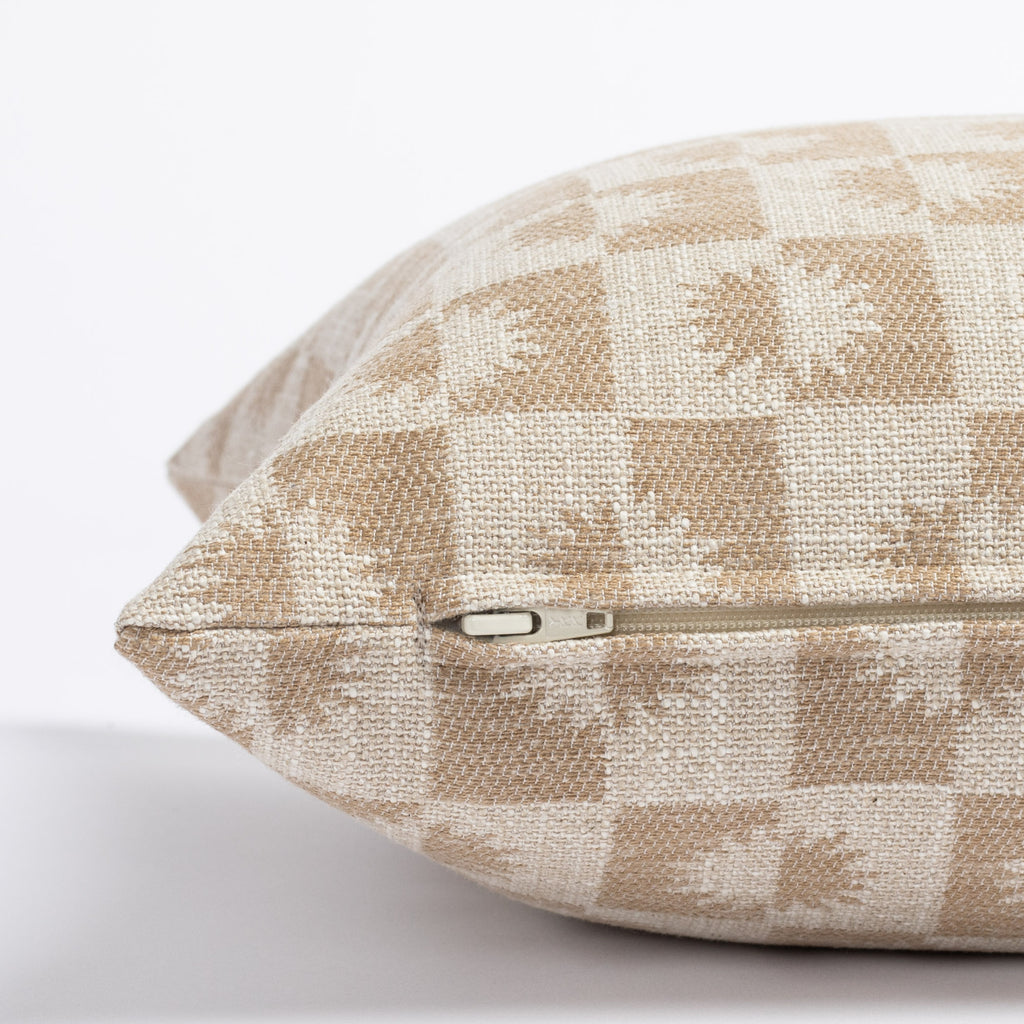 a beige and light brown sun motif checker patterned lumbar throw pillow : close up zipper view