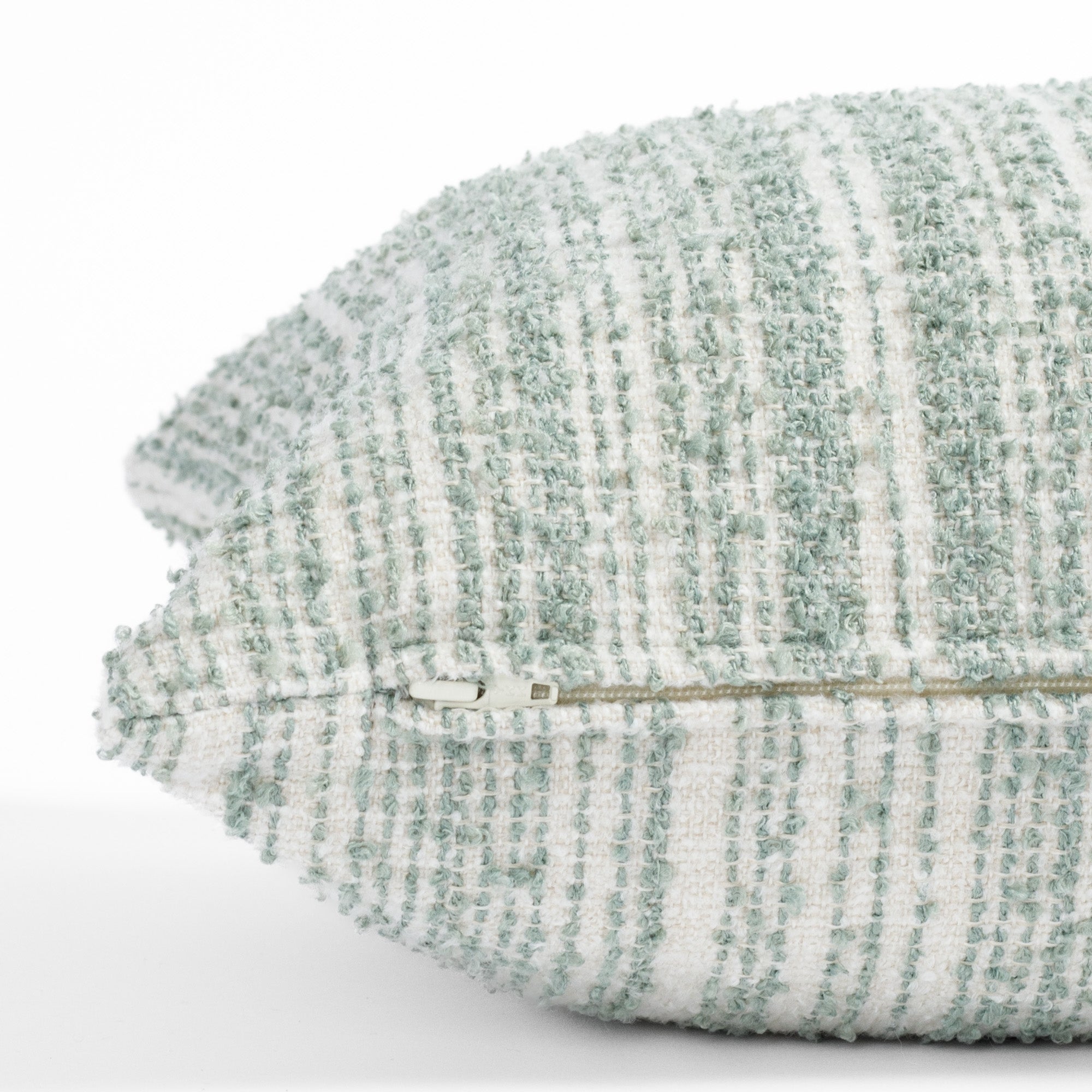 a soft white and blue green boucle striped lumbar pillow : close up zipper view