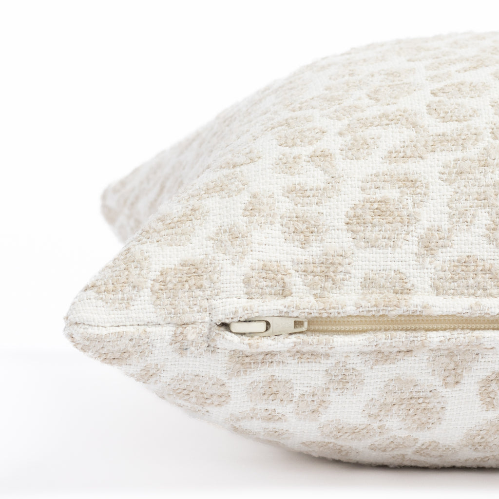 a white, cream and taupe specked cheetah patterned indoor outdoor lumbar pillow : close up zipper  view
