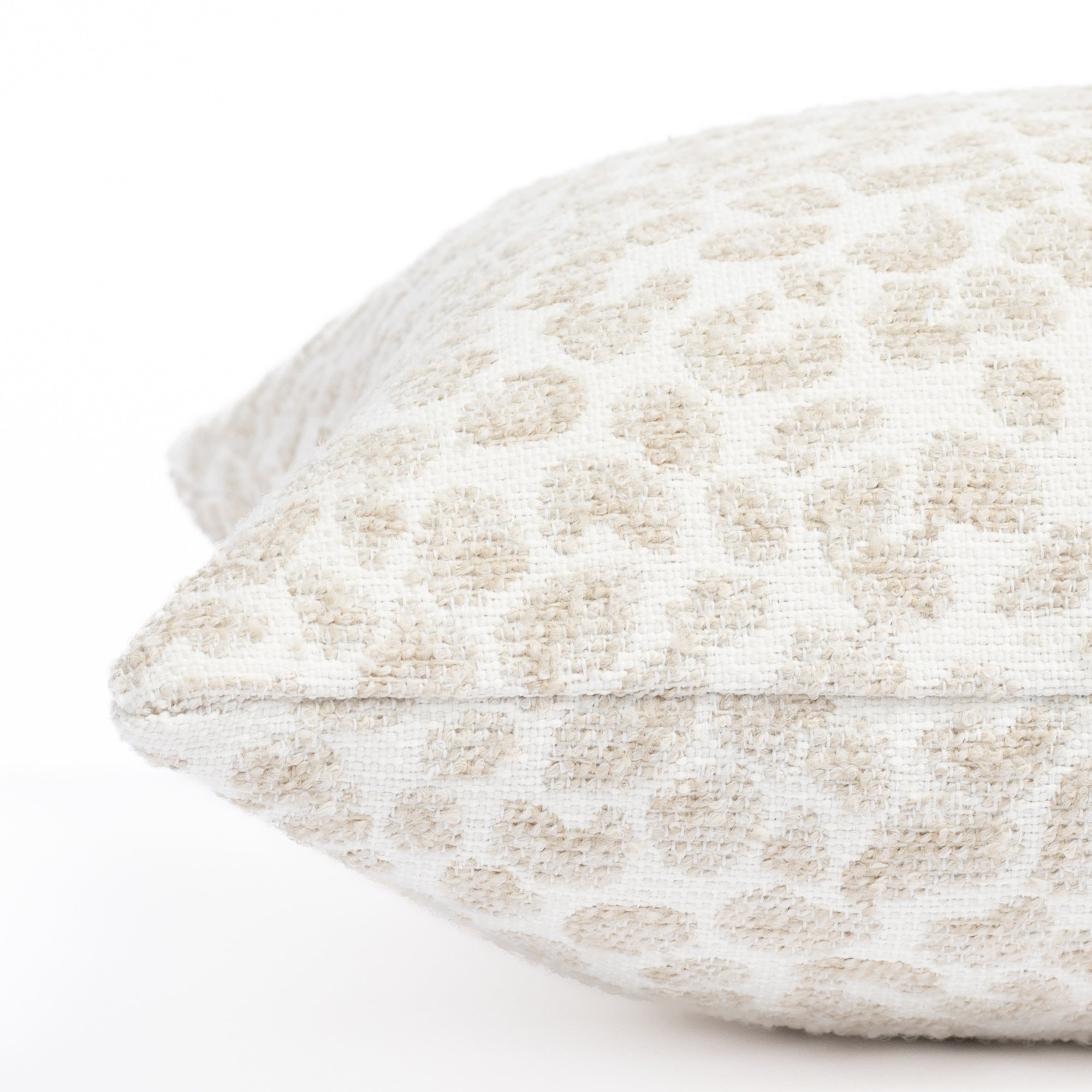 a white, cream and taupe specked cheetah patterned indoor outdoor lumbar pillow : close up side view