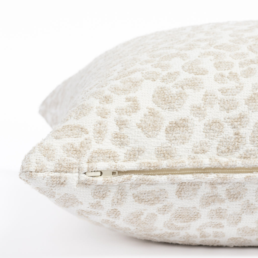 a creamy white and taupe beige speckled cheetah patterned indoor outdoor pillow : close up zipper view