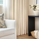 Lyra Fabric, Parchment by Tonic Living — linen-blend drapery fabric with a warm white and beige floral block print, shown in a living room with Manor Tapestry 20x20 Pillow, Sage.