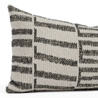 Close-up of the Mallia Carbon 12x24 decorative outdoor lumbar cushion by Tonic Living, showcasing the organic black pattern and luxurious woven texture in off-white and beige tones.