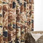 Tonic Living Marbella Inkwell abstract floral drapery fabric shown as curtains featuring painterly blooms in rich browns and blue.