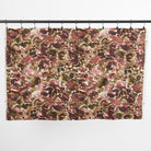 One yard of Tonic Living Marbella Rose floral fabric hanging from clips, showing the full-scale burgundy and pink abstract pattern.