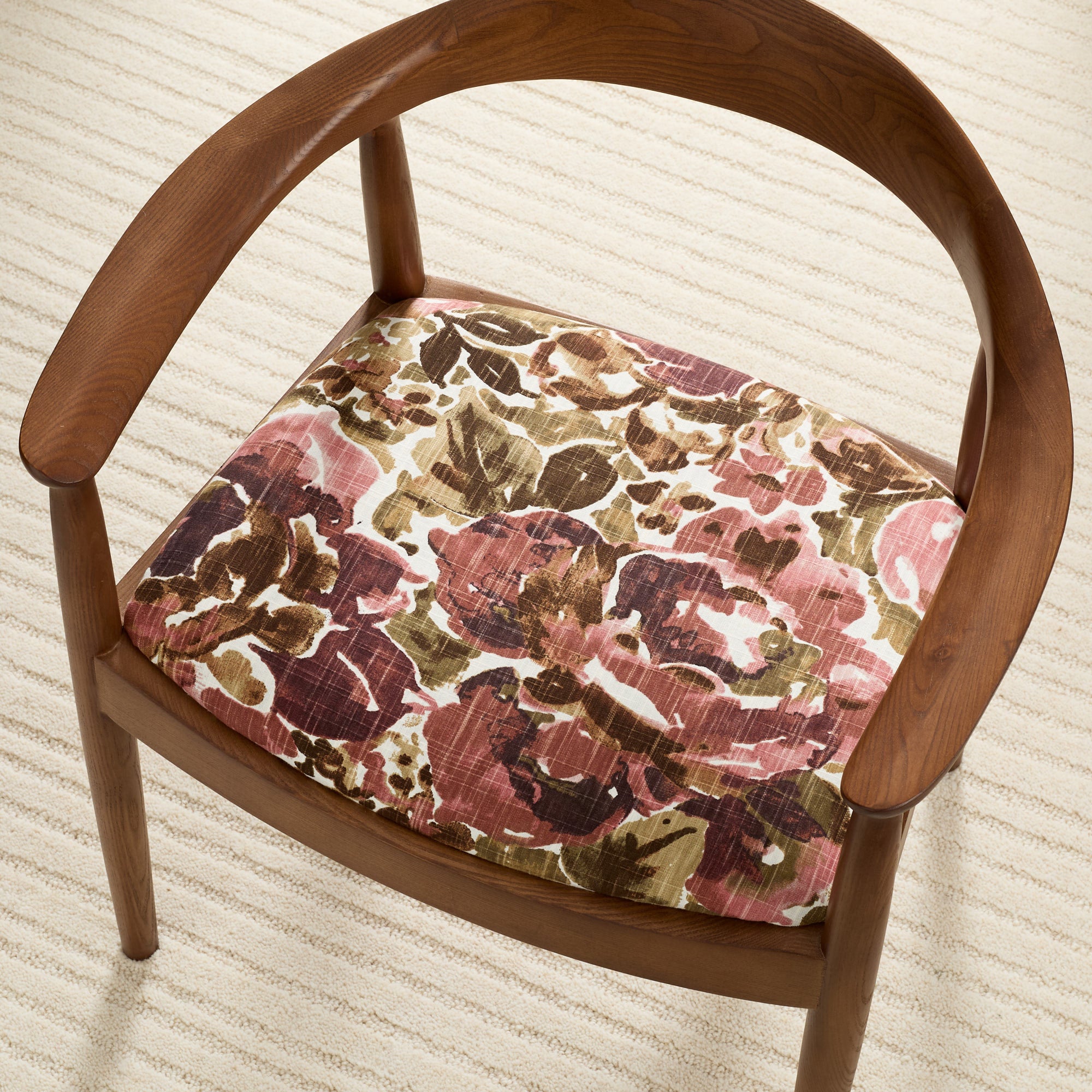 Tonic Living Marbella Rose floral upholstery fabric shown on a dining chair seat in burgundy and dusty pink tones.