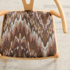 Tonic Living Mendoza Fig upholstery fabric shown on a dining chair in warm multicolour tones.