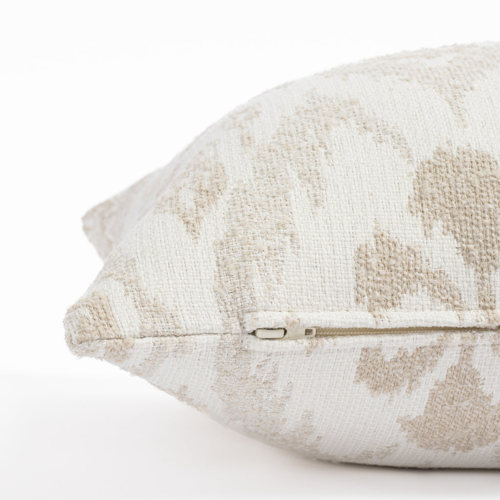 a white, cream and taupe large scale ikat patterned, chenille textured bolster pillow : close up zipper view