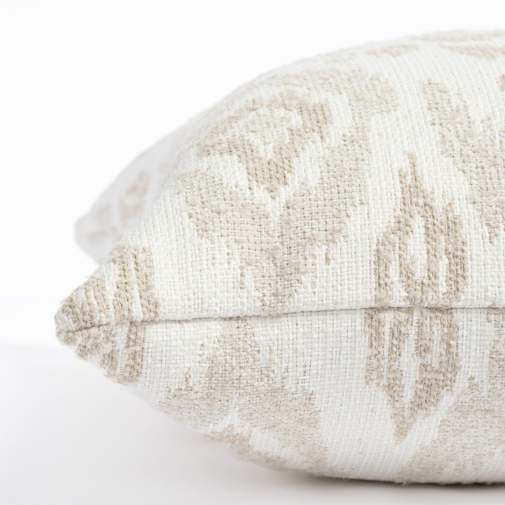 a white, cream and taupe large scale botanical ikat patterned outdoor pillow : close up side view