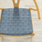 Tonic Living Nile Indigo upholstery fabric shown on a dining chair seat in a blue and white tie-dye stripe.