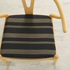 Tonic Living Odessa InsideOut Carbon indoor/outdoor upholstery fabric on a dining chair seat in black and tan stripe.