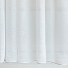 a soft white sheer drapery fabric : close up view of weighted edge