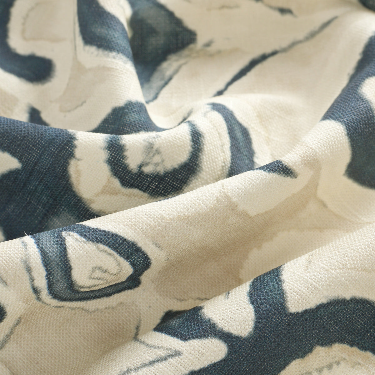 Close up of Tonic Living Paloma Ink drapery fabric showing stylized navy blue flowers and scrolling leaves with a watercolour effect.
