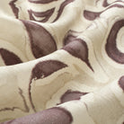Close up of Tonic Living Paloma Mauve drapery fabric showing stylized muted purple flowers and scrolling leaves with a watercolour effect.