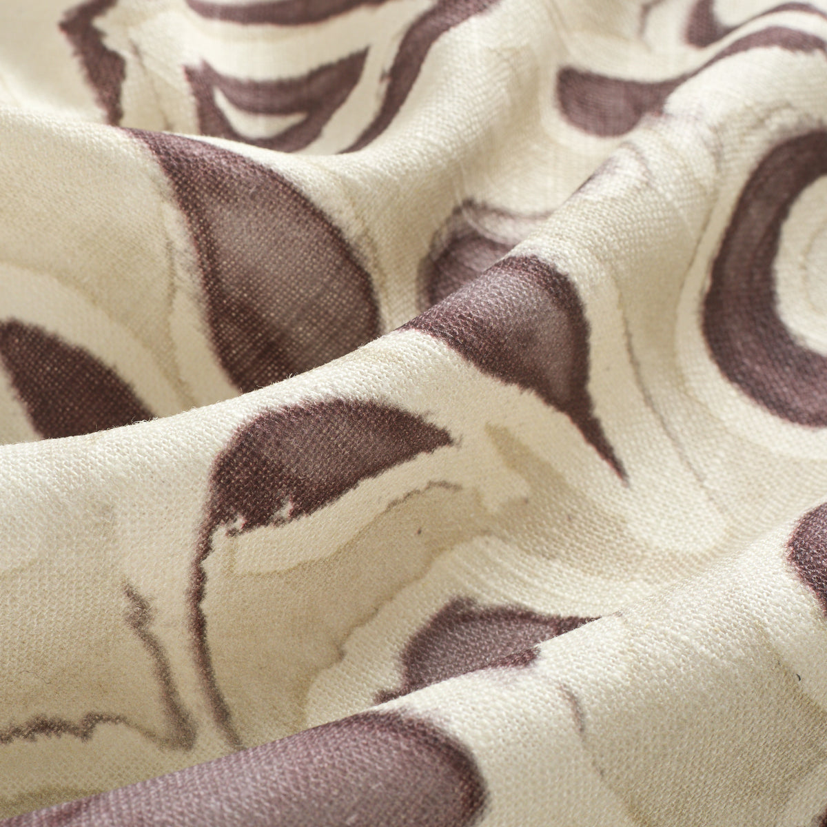 Close up of Tonic Living Paloma Mauve drapery fabric showing stylized muted purple flowers and scrolling leaves with a watercolour effect.